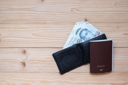 Money banknote in black wallet with Passport on wooden table, Top view and copy space. Time to Travel in Singapore conceptの写真素材