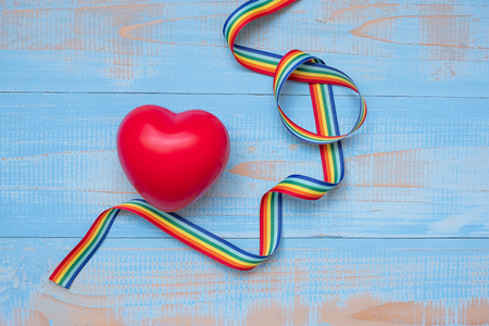 red heartr shape with LGBTQ Rainbow ribbon on blue pastel wooden background for Lesbian, Gay, Bisexual, Transgender and Queer communityの写真素材