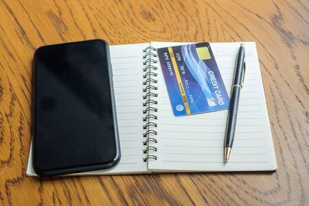 notebook, credit card and touchscreen smartphone on table. business, lifestyle, technology, ecommerce and online payment conceptの写真素材