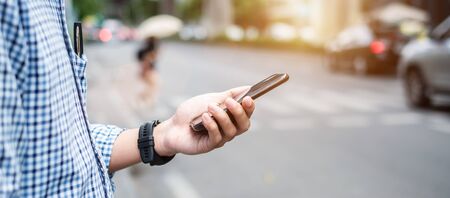 Young man tourist or casual businessman ordering taxi via cab application on smartphone in city street, Male traveler using mobile phone and Searching direction on digital map at Bangkok, Thailandの写真素材