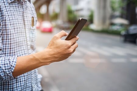 Young man tourist or casual businessman ordering taxi via cab application on smartphone in city street, Male traveler using mobile phone and Searching direction on digital map at Bangkok, Thailandの写真素材