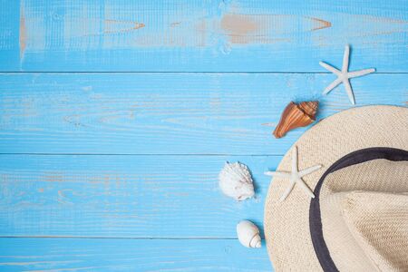 beach accessories; hat, sunscreen, sunglasses, slippers and shell decoration on blue wood, summer...