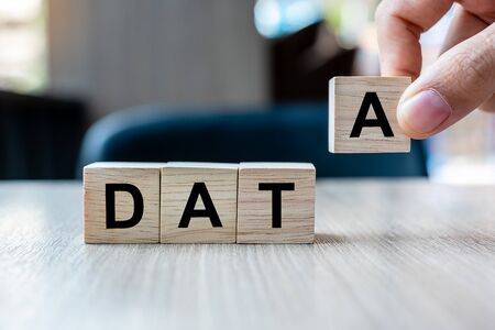 Businessman hand holding wooden cube block with DATA business word on table background. Database, Financial and marketing conceptsの写真素材
