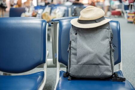 gray business backpack with hat on seat at the interior of airport terminal. Business and Travel conceptの写真素材