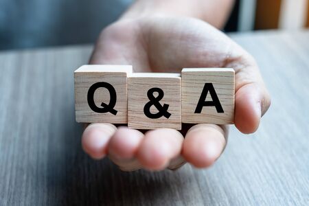 Businessman hand holding Q&A word with wooden cube block. FAQ( frequency asked questions), Answer, Question & Ask, Information, Communication and Brainstorming Conceptsの写真素材