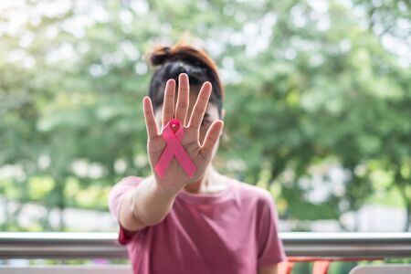 October Breast Cancer Awareness month, Woman in pink T- shirt with hand holding Pink Ribbon for supporting people living and illness. Healthcare, International Women day and World cancer day conceptの写真素材