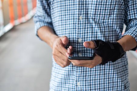 Young man holding his wrist pain because using smartphone long time. Disease and healthcare conceptの写真素材