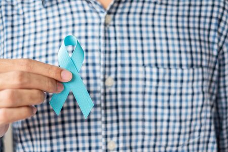 November Prostate Cancer Awareness month, Man in blue shirt with hand holding Blue Ribbon for supporting people living and illness. Healthcare, International men, Father and World cancer day conceptの写真素材