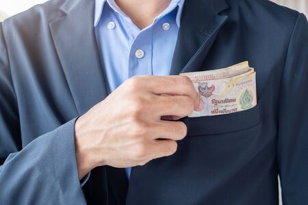 Businessman hand holding Thai Baht banknote stack. business, money, investment, finance and payment conceptsの写真素材