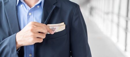 Businessman hand holding Thai Baht banknote stack. business, money, investment , finance and payment conceptsの写真素材