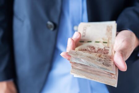 Businessman hand holding Thai Baht banknote stack. business, money, investment, finance and payment conceptsの写真素材