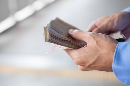Businessman hand holding Thai Baht banknote stack. business, money, investment, finance and payment conceptsの写真素材