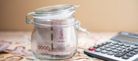 1000 Thai Baht banknote background and Money glass jar with Calculator. business, investment, retirement planning, finance and Saving for the future conceptsの写真素材