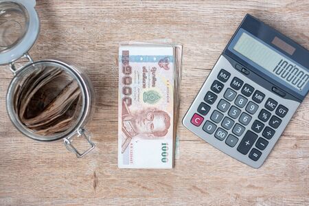 Businessman hand holding Thai Baht banknote stack and using calculator. business, accounting, money, investment, finance and payment conceptsの写真素材