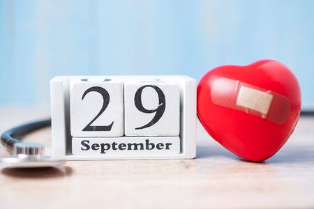 September 29 of white calendar and Stethoscope with Red heart shape on wooden background. Healthcare, life Insurance and World Heart Day conceptの写真素材