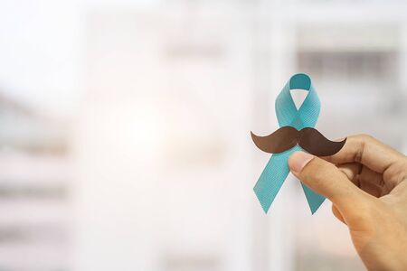 November Prostate Cancer Awareness month, Man holding Blue Ribbon with mustache  for supporting people living and illness. Healthcare, International men, Father and World cancer day conceptの写真素材
