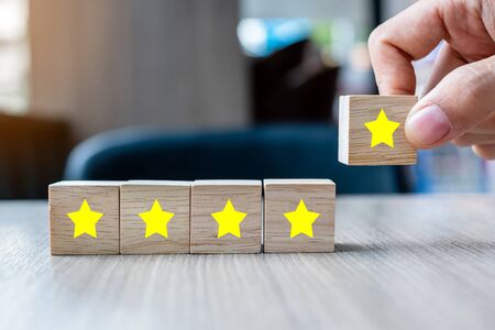 customer holding wooden blocks with the five star symbol. Customer reviews, feedback, rating, ranking and service concept.の写真素材