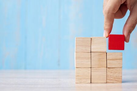 Businessman hand placing or pulling Red wooden block on the building. Business planning, Risk Management, Solution, strategy, different and Unique Conceptsの写真素材