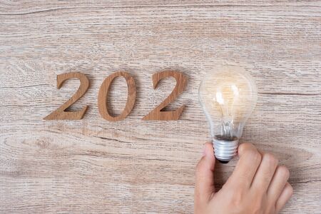 2020 Happy New year with Businessman holding lightbulb with crumbled paper and wooden number on table. New Start, Idea, Creative, Innovation, Resolution, Solution, Strategy, Goals and Mission conceptの写真素材