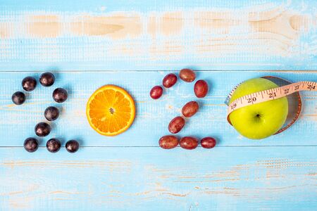 2020 Happy New Year with fruits, Black grapes, Mandarin Orange, Red grapes and green apple on blue wood background. Goals, Healthy, Healthcare, Resolution, New Start and Holiday concept.の写真素材