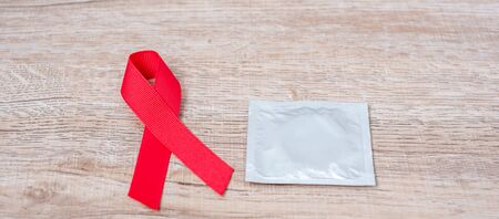 December World Aids Day Awareness month, Red Ribbon and condom on wood background for supporting people living and illness. Healthcare and safe sex conceptの写真素材