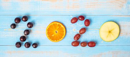 2020 Happy New Year and New You with fruits, Black grapes, Orange, Red grapes and green apple on blue wood background. Goals, Healthy, Healthcare, Resolution, Time to New Start and dieting concept.の写真素材