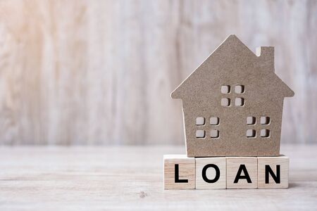 Wood block with LOAN text and house model on wooden background. Banking, real estate, Property investment, home mortgage, financial and savings conceptsの写真素材