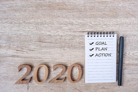 2020 Happy New years with Goal, plan, action on paper notebook, pen and wooden number on table. New...