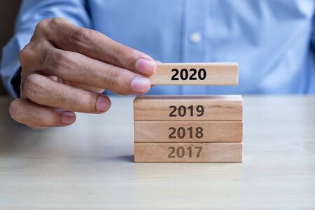 Businessman hand pulling 2020 wooden building blocks on table background. Business planning, Risk Management, Resolution, strategy, solution, goal, New Year New You and happy holiday conceptsの写真素材