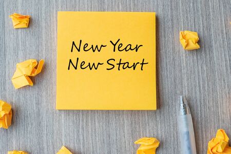 NEW YEAR NEW START word on yellow note with pen and crumbled paper on wooden table background. Resolutions, Strategy and Goal conceptの写真素材