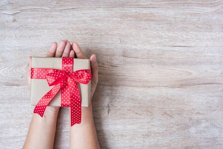 woman holding gift box on wooden background, preparation for holiday concept, Happy New Year and Xmas Holidays. Top viewの写真素材