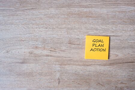 goal, plan and action word on yellow paper note on wooden table background. Strategy, mission, vision conceptの写真素材