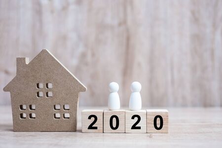 2020 Happy New Year with house model and people  on wooden background. Banking, real estate, investment, financial, savings and New Year Resolution conceptsの写真素材