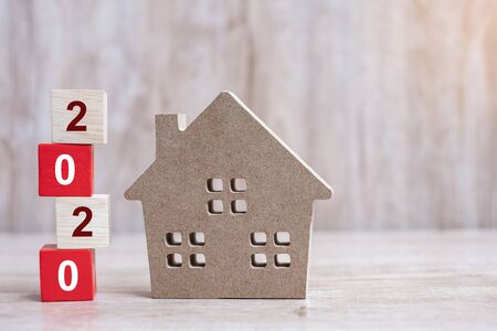 2020 Happy New Year with house model on wooden background. Banking, real estate, investment, financial, savings and New Year Resolution conceptsの写真素材