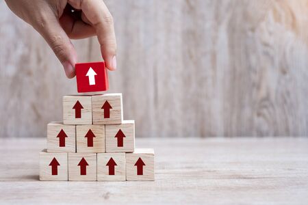 Businessman hand placing or pulling Red arrow wooden block on table background. Business Growth, Improvement, strategy and Successful Conceptsの写真素材