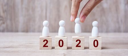 hand holding businessman over block building with 2020 text. leadership, business, team, teamwork and New Year Resolution conceptの写真素材