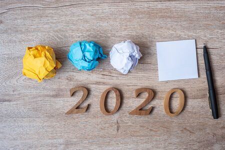2020 NEW YEAR WITH blank yellow note  and crumbled paper on wooden table background. NEW START, Strategy and Goal conceptの写真素材