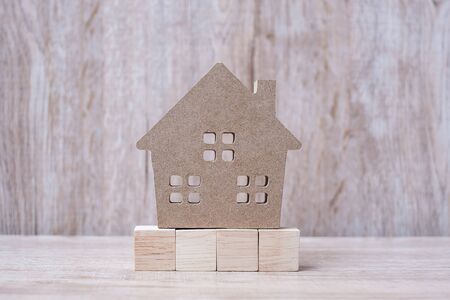 Wood block and house model on wooden background. Banking, real estate, Property investment, home mortgage, financial and savings conceptsの写真素材