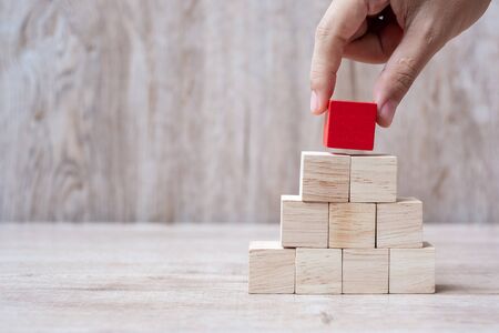 Businessman hand placing or pulling Red wooden block on the building. Business planning, Risk Management, Solution, strategy, different and Unique Conceptsの写真素材