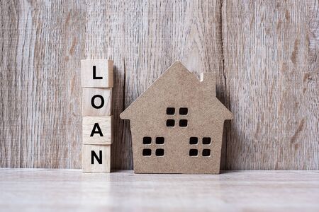 Wood block with LOAN text and house model on wooden background. Banking, real estate, Property investment, home mortgage, financial and savings conceptsの写真素材