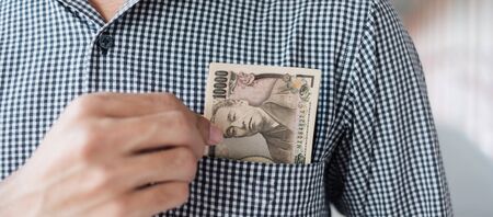 Businessman hand holding Japanese Yen banknote stack. business, money, investment, finance and payment conceptsの写真素材