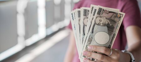 Businesswoman hand holding Japanese Yen banknote stack. business, money, investment, finance and payment conceptsの写真素材