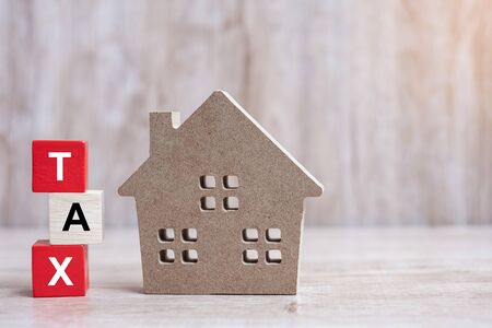 Wood block with TAX text and house model on wooden background. Banking, real estate, Property investment, home mortgage, financial and savings conceptsの写真素材