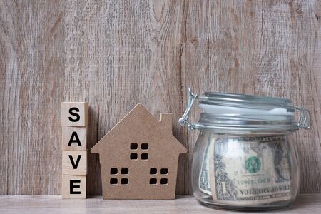 Wood house model and money glass jar, American dollar banknote. real estate, Property investment, home mortgage financial and savings conceptsの写真素材