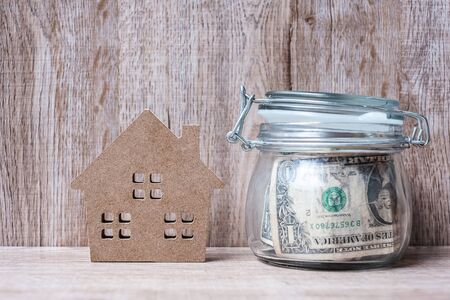 Wood house model and money glass jar, American dollar banknote. real estate, Property investment, home mortgage financial and savings conceptsの写真素材