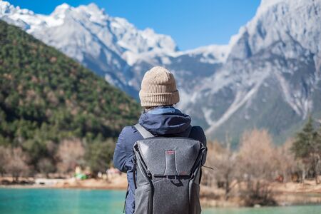 Young man traveler traveling at Blue Moon Valley, landmark and popular spot inside the Jade Dragon Snow Mountain Scenic Area, near Lijiang Old Town. Lijiang, Yunnan, China. Solo travel conceptの写真素材