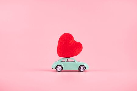 Red heart shape decoration on mini car toy with copy space for text on pink background. Love, Wedding, Romantic and Happy Valentine day holiday conceptの写真素材