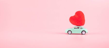 Red heart shape decoration on mini car toy with copy space for text on pink background. Love, Wedding, Romantic and Happy Valentine day holiday conceptの写真素材