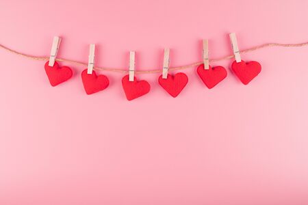 Red heart shape decoration hanging on line with copy space for text on pink background. Love, Wedding, Romantic and Happy Valentine day holiday conceptの写真素材