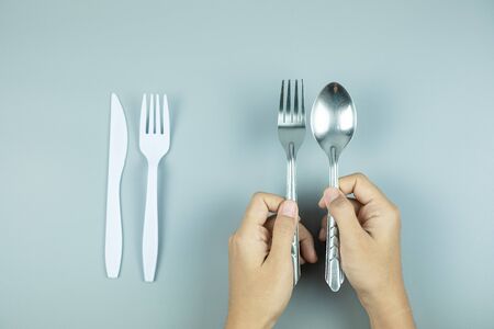 Man holding Stainless Steel spoon and fork over white plastic tool. Environmental Protection, Zero waste, Reusable, Say No Plastic, World Environment day and Earth day conceptの写真素材